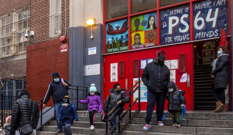 Parents pick up their children while wearing masks outside of P.S. 64 in the East Village neighborhood of Manhattan,  Tuesday, Dec. 21, 2021, in New York. (AP Photo/Brittainy Newman) ** FILE **