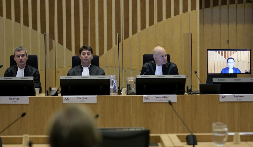 Presiding Judge Hendrik Steenhuis, right, looks at a television monitor during the ongoing trial and criminal proceedings regarding the downing of Malaysia Airlines flight MH17, at the high security court at Schiphol airport, near Amsterdam, Netherlands, Monday, Dec. 20, 2021. Prosecutors are scheduled to begin explaining the evidence and their case to judges Monday in the murder trial of three Russians and a Ukrainian charged with involvement in downing Malaysia Airlines flight MH17 over eastern Ukraine in 2014, killing all 298 passengers and crew. (AP Photo/Peter Dejong)