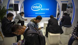 Attendees look at their smartphones at a booth from chipmaker Intel at the PT Expo in Beijing on Oct. 31, 2019. Intel Corp. apologized Thursday, Dec. 23, 2021, for asking suppliers to avoid sourcing goods from Xinjiang after the chipmaker became the latest foreign brand to face the fury of state media regarding the region, where the ruling Communist Party is accused of widespread abuses. (AP Photo/Mark Schiefelbein)