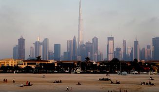 People enjoy the beach in front of the city skyline with the world tallest tower, Burj Khalifa, in Dubai, United Arab Emirates, Friday, Feb. 12, 2021. The multibillion-dollar world&#39;s fair in Dubai has warned that some venues on site may shut down as coronavirus cases rapidly rise in the United Arab Emirates. (AP Photo/Kamran Jebreili, File)