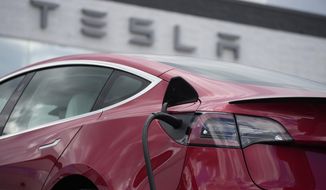 A 2021 Model 3 sedan charges at a Tesla dealership in Littleton, Colo., on June 27, 2021. Electric vehicle sales nearly doubled in the U.S. and worldwide in 2021. (AP Photo/David Zalubowski, File)