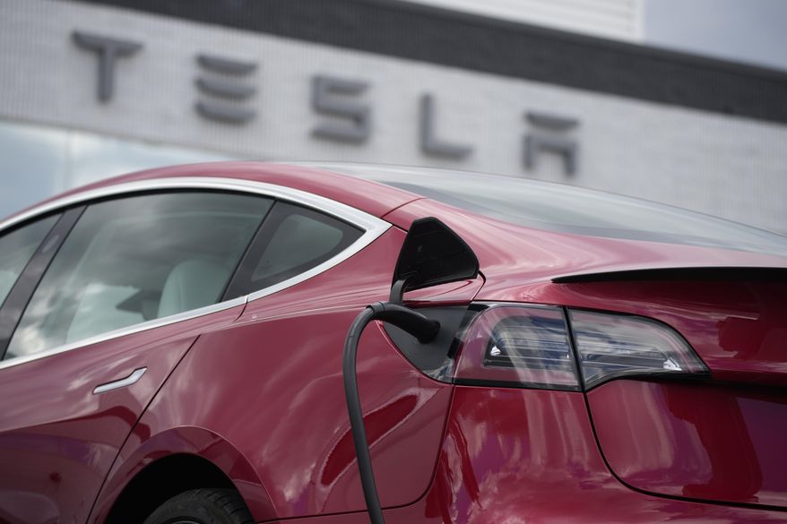 A 2021 Model 3 sedan charges at a Tesla dealership in Littleton, Colo., on June 27, 2021. Electric vehicle sales nearly doubled in the U.S. and worldwide in 2021. (AP Photo/David Zalubowski, File)