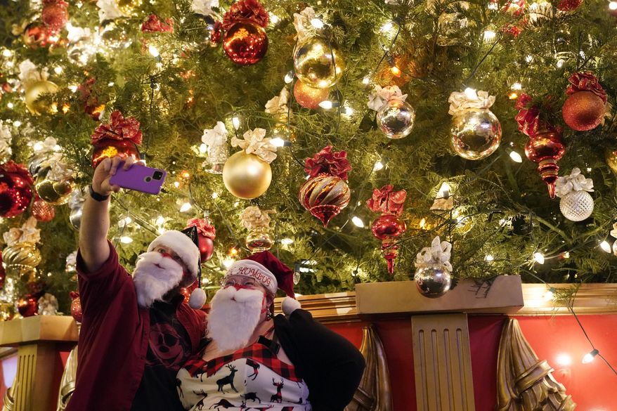 Visitors take photos under a Christmas tree amid the COVID-19 pandemic at a shopping district Wednesday, Dec. 22, 2021, in Los Angeles. (AP Photo/Marcio Jose Sanchez) ** FILE **
