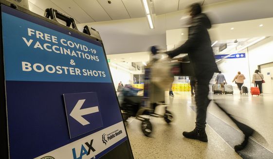 A Free COVID-19 Vaccination and Booster Shots sign is posted at the Los Angeles International Airport in Los Angeles, Wednesday Dec. 22, 2021. People traveling during the holiday season can get free COVID-19 vaccinations and booster shots at LAX on two consecutive Wednesdays -- today and Dec. 29. The pop-up clinic, located at the Lower/Arrivals Level of the Tom Bradley International Terminal, will be open from 11 a.m. to 5 p.m. on the two days. (AP Photo/Ringo H.W. Chiu)