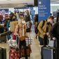 Holiday travelers wearing face masks line to check in at the Los Angeles International Airport in Los Angeles, Wednesday, Dec. 22, 2021. (AP Photo/Ringo H.W. Chiu) ** FILE **