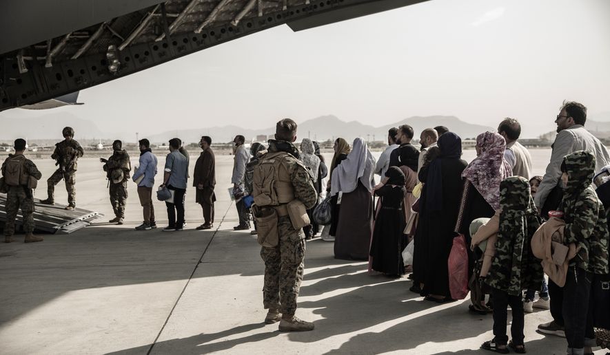 In this image provided by the U.S. Marine Corps, evacuees wait to board a Boeing C-17 Globemaster III during an evacuation at Hamid Karzai International Airport in Kabul, Afghanistan, Monday, Aug. 30. 2021. (Staff Sgt. Victor Mancilla/U.S. Marine Corps via AP, File)