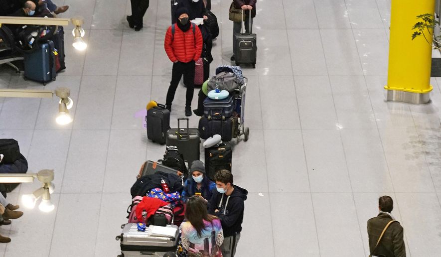 Travelers wait in line to be tested for COVID-19 at Logan Airport, Tuesday, Dec. 21, 2021, in Boston. At least three major airlines say they have canceled dozens of flights, Friday, Dec. 24, because illnesses largely tied to the omicron variant of COVID-19 have taken a toll on flight crew numbers during the busy holiday travel season. (AP Photo/Charles Krupa)