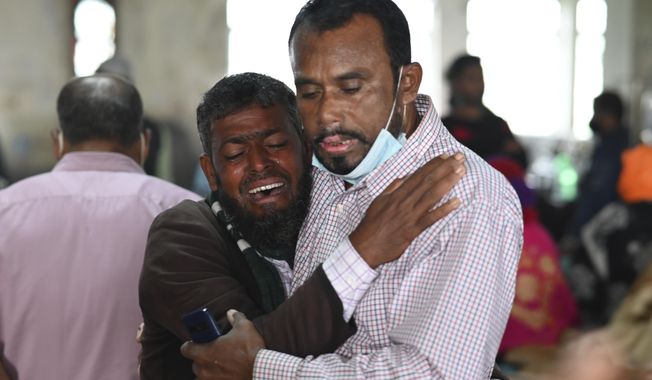 A person consoles his relative who is unable to find his five years old son travelling in a ferry which caught fire, at a government medical hospital, in Barishal, Bangladesh, Friday, Dec. 24, 2021. Bangladesh fire services say at least 37 passengers have been killed and many others injured in a massive fire that swept through a ferry on the southern Sugandha River. The blaze broke out around 3 a.m. Friday on the ferry packed with 800 passengers. (AP Photo/Niamul Rifat)