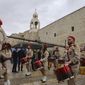 Palestinian scout band members parade through Manger Square at the Church of the Nativity, traditionally believed to be the birthplace of Jesus Christ, during Christmas celebrations, in the West Bank city of Bethlehem, Friday, Dec. 24, 2021. The biblical town of Bethlehem is gearing up for its second straight Christmas Eve hit by the coronavirus with small crowds and gray, gloomy weather dampening celebrations Friday in the traditional birthplace of Jesus. (AP Photo/Mahmoud Illean)