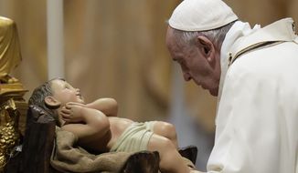 Pope Francis is about to kiss a statue of Baby Jesus as he celebrates Christmas Eve Mass, at St. Peter&#39;s Basilica, at the Vatican, Friday Dec. 24, 2021. (AP Photo/Alessandra Tarantino)