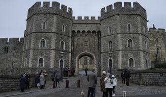 Tourists stand in front of the Henry VII gate and take pictures at Windsor castle at Windsor, England on Christmas Day, Saturday, Dec. 25, 2021. (AP Photo/Alastair Grant)