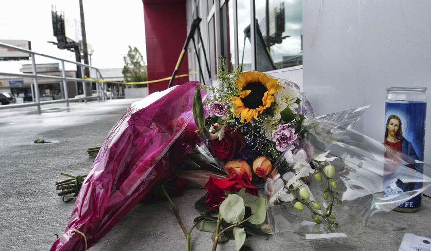 A votive candle and flowers are left for a teen who was fatally shot at a department store in the North Hollywood section of Los Angeles on Saturday, Dec. 25, 2021. The coroner&#39;s office has identified the 14-year-old girl who was fatally shot by Los Angeles police the day before, when officers fired on an assault suspect and a bullet went through the wall and struck the girl as she was in a clothing store dressing room. (AP Photo/Richard Vogel)