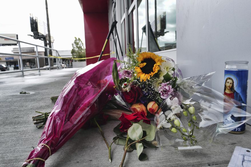 A votive candle and flowers are left for a teen who was fatally shot at a department store in the North Hollywood section of Los Angeles on Saturday, Dec. 25, 2021. The coroner&#x27;s office has identified the 14-year-old girl who was fatally shot by Los Angeles police the day before, when officers fired on an assault suspect and a bullet went through the wall and struck the girl as she was in a clothing store dressing room. (AP Photo/Richard Vogel)