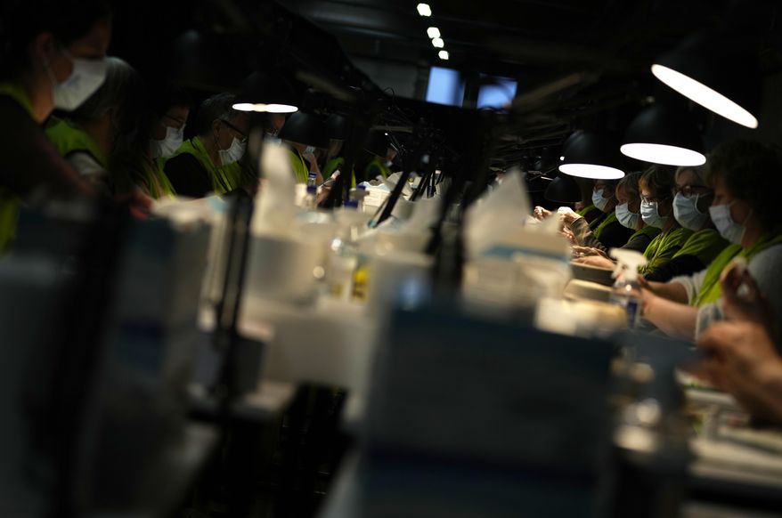 Pharmacists fill syringes from vials of the Moderna booster vaccine at the Antwerp Expo vaccine center in Antwerp, Belgium on Monday, Dec. 27, 2021. In Belgium, many flocked to their local vaccine center to receive their booster shots and stay ahead of the surging omicron infections. Others faced their first real test of the latest COVID-19 measures on Monday, with shopping reduced to a maximum of two along with closures of movie theaters and concert halls. (AP Photo/Virginia Mayo)