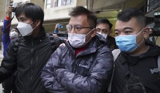Senior editor of &amp;quot;Stand News&amp;quot; Ronson Chan, center, is arrested by police officers in Hong Kong, Wednesday, Dec. 29, 2021. Hong Kong police said they arrested several of its staff, including Chan, who is also head of the Hong Kong Journalists Association, early Wednesday morning for conspiracy to publish a seditious publication. (AP Photo)