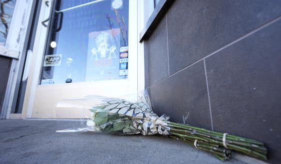 Bouquets of flowers are placed outside the door of a tattoo parlor along South Broadway Tuesday, Dec. 28, 2021 in Denver, one of the scenes of a shooting spree that left five people dead—including the suspected shooter Monday evening—and left a few more people wounded. The spree spread from the core of Denver to the western suburb of Lakewood where the suspect was shot and killed by police near a busy intersection in a bustling shopping district. (AP Photo/David Zalubowski)