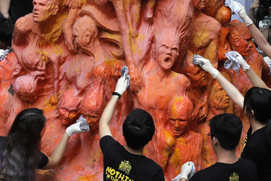 University students clean the "Pillar of Shame" statue, a memorial for those killed in the 1989 Tiananmen crackdown, at the University of Hong Kong, June 4, 2019. For Hong Kong’s pro-democracy movement, 2021 has been a year in which the city’s authorities and the central government in Beijing stamped out nearly everything it had stood for. (AP Photo/Kin Cheung, File)
