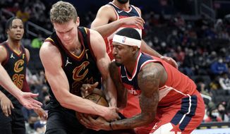Washington Wizards guard Bradley Beal, right, battles for the ball against Cleveland Cavaliers forward Lauri Markkanen, left, during the first half of an NBA basketball game, Thursday, Dec. 30, 2021, in Washington. (AP Photo/Nick Wass)