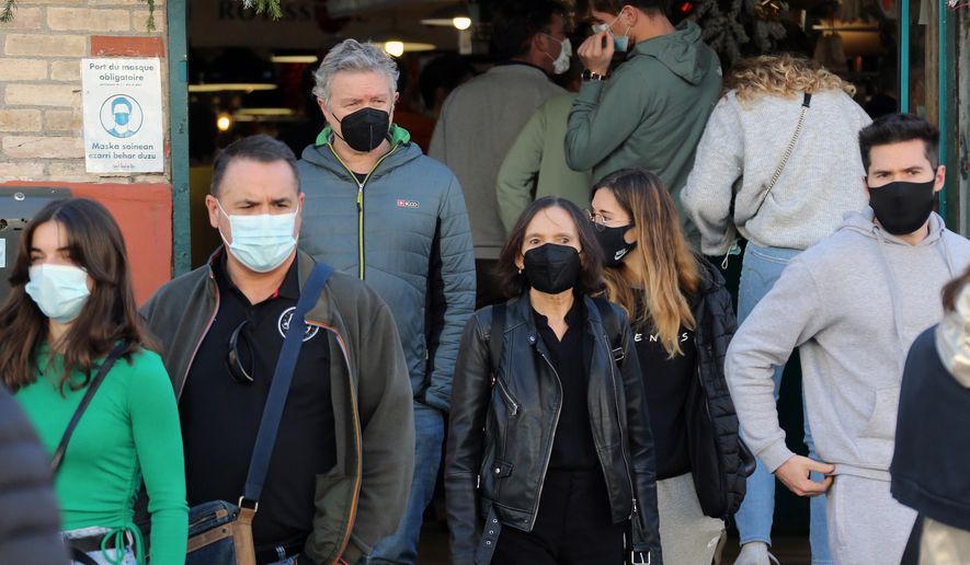 People wearing face mask walk on the street in Saint Jean de Luz, southwestern France, Thursday, Dec.30, 2021. The French government announced this week new measures to fight the spreading of the virus as France reported a record high of 208,000 new infections on Wednesday. Mask-wearing is already mandatory inside shops, public facilities, office buildings and public transports across France. (AP Photo/Bob Edme)