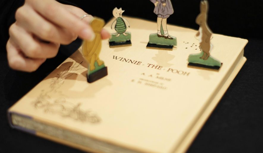 FILE - A first U.S. edition of Winnie the Pooh signed by the author A.A. Milne and illustrator E.H. Shepard is displayed with cut-outs representing characters from the book at offices of the Sotheby&#39;s auction house in London, Monday, Dec. 15, 2008.   “Winnie the Pooh” and “The Sun Also Rises” are going public. A.A. Milne’s children’s book and Ernest Hemingway’s novel are among the works from 1926 whose copyrights will expire Saturday, Jan. 1, 2022, putting them in the public domain in 2022.  (AP Photo/Matt Dunham, File)