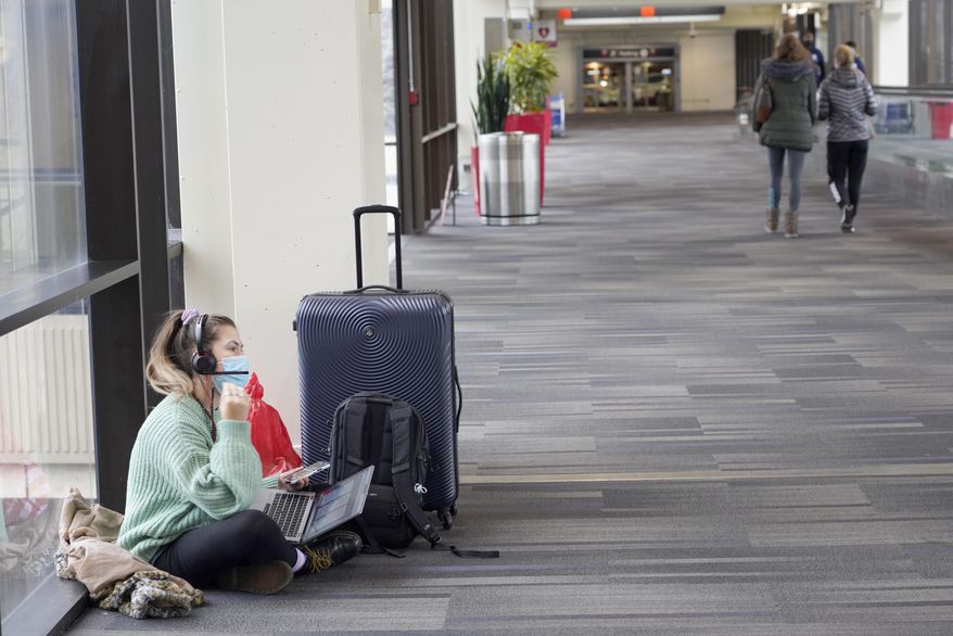 Katelyn Darrow gets some work done on her laptop as she waits to board her flight at the Philadelphia International Airport Friday, Dec. 31, 2021, in Philadelphia. Winter weather and crew members infected with COVID-19 have forced airlines to spike thousands of U.S. flights over the past week, complicating travel plans for many people during the busy holiday season. (AP Photo/Michael Perez)