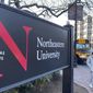 Pedestrians walk near a Northeastern University sign on the school&#39;s campus in Boston, Jan. 31, 2019. At Northeastern University in Boston, one of a growing number of schools requiring boosters, students are returning to campus as planned.(AP Photo/Rodrique Ngowi, File)