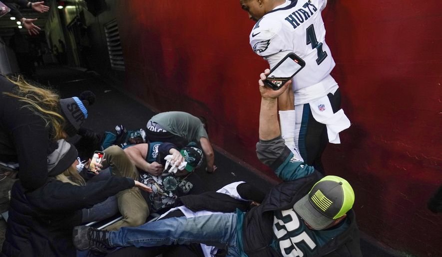 Fans hit the ground infront of Philadelphia Eagles quarterback Jalen Hurts (1) after a railing collapsed following the end of an NFL football game, Sunday, Jan. 2, 2022, in Landover, Md. Philadelphia won 20-16. (AP Photo/Alex Brandon)