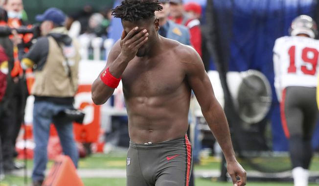 Tampa Bay Buccaneers wide receiver Antonio Brown wipes his face as he leaves the field after throwing his equipment into the stands while his team is on offense during the third quarter of an NFL football game against the New York Jets, Sunday, Jan. 2, 2022, in East Rutherford, N.J. (Andrew Mills/NJ Advance Media via AP)