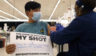 Lucas Kittikamron-Mora, 13, holds a sign in support of COVID-19 vaccinations as he receives his first Pfizer vaccination at the Cook County Public Health Department, May 13, 2021 in Des Plaines, Ill. The U.S. is expanding COVID-19 boosters as it confronts the omicron surge, with the Food and Drug Administration allowing extra Pfizer shots for children as young as 12. Boosters already are recommended for everyone 16 and older, and federal regulators on Monday, Jan. 3, 2022 decided they’re also warranted for 12- to 15-year-olds once enough time has passed since their last dose. (AP Photo/Shafkat Anowar) **FILE**