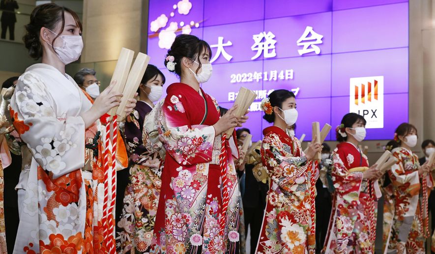 Workers attend a ceremony to mark the first trading day of the year at Osaka Exchange in Osaka, western Japan Tuesday, Jan. 4, 2022. The Japanese sign reads "The first trading day." (Kyodo News via AP)