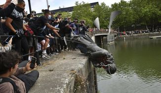 Protesters throw a statue of Edward Colston into the Bristol harbour during a Black Lives Matter protest rally, Bristol, England, June 7, 2020. Four anti-racism demonstrators were cleared Wednesday Jan. 5, 2022, of criminal damage in the toppling of a statue of a 17th-century slave trader during a Black Lives Matter protest in southwestern England 18 months ago. (Ben Birchall/PA via AP, File)  **FILE**