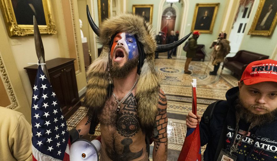 Jacob Anthony Chansley, center, with other insurrectionists who supported then-President Donald Trump, are confronted by U.S. Capitol Police in the hallway outside of the Senate chamber in the Capitol, Jan. 6, 2021, in Washington. (AP Photo/Manuel Balce Ceneta)