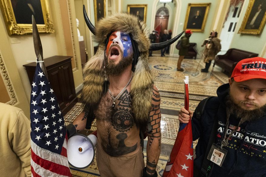 Jacob Anthony Chansley, center, with other insurrectionists who supported then-President Donald Trump, are confronted by U.S. Capitol Police in the hallway outside of the Senate chamber in the Capitol, Jan. 6, 2021, in Washington. (AP Photo/Manuel Balce Ceneta)