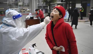 In this photo released by China&#39;s Xinhua News Agency, a worker wearing protective gear gives a COVID-19 test to a woman at a testing site in Xi&#39;an in northwestern China&#39;s Shaanxi Province, Tuesday, Jan. 4, 2022. China is reporting a major drop in local COVID-19 infections in the northern city of Xi&#39;an, which has been under a tight lockdown for the past two weeks. (Tao Ming/Xinhua via AP)