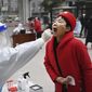 In this photo released by China&#39;s Xinhua News Agency, a worker wearing protective gear gives a COVID-19 test to a woman at a testing site in Xi&#39;an in northwestern China&#39;s Shaanxi Province, Tuesday, Jan. 4, 2022. China is reporting a major drop in local COVID-19 infections in the northern city of Xi&#39;an, which has been under a tight lockdown for the past two weeks. (Tao Ming/Xinhua via AP)