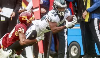 Philadelphia Eagles running back Boston Scott (35) carries the ball as Washington Football Team cornerback Kendall Fuller (29) defends during the first half of an NFL football game Sunday, Jan. 2, 2022 in Landover, Md. (Shaban Athuman/Richmond Times-Dispatch via AP)