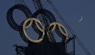 A worker labors to assemble the Olympic Rings onto of a tower on the outskirts of Beijing, China, Wednesday, Jan. 5, 2022. Beijing will host the Winter Olympics in a month&#39;s time, making it the world&#39;s first dual Olympic city having hosted both the Summer and Winter games. (AP Photo/Ng Han Guan)