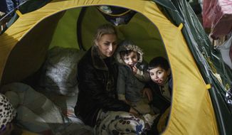 A woman sits with her children inside the tent at the &quot;Bruzgi&quot; checkpoint logistics center at the Belarus-Poland border near Grodno, Belarus, Thursday, Dec. 23, 2021. About 4,000 Iraqis stuck on the border of Belarus and several other European countries including Poland, Latvia and Lithuania will be returning home after the government in Baghdad organized almost a dozen repatriation flights for its citizens. (AP Photo/Pavel Golovkin)