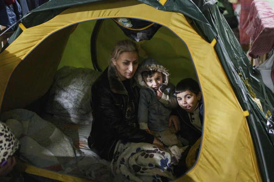 A woman sits with her children inside the tent at the "Bruzgi" checkpoint logistics center at the Belarus-Poland border near Grodno, Belarus, Thursday, Dec. 23, 2021. About 4,000 Iraqis stuck on the border of Belarus and several other European countries including Poland, Latvia and Lithuania will be returning home after the government in Baghdad organized almost a dozen repatriation flights for its citizens. (AP Photo/Pavel Golovkin)