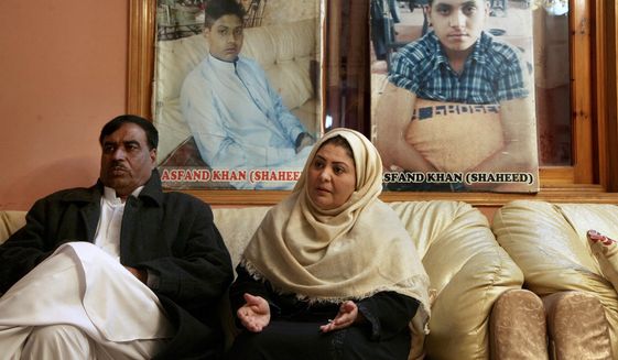 Pakistani mother Shahana with her husband Ajoon Khan sit next to photos of their son Asfand Khan, who was killed in a 2014 assault by Pakistani Taliban militants on an army public school, during an interview with The Associated Press, in Peshawar, Pakistan, Wednesday, Dec. 29, 2021. Each year on Jan. 17 Shahana bakes a cake and invites friends to her home to sing happy birthday, even light a candle but it&#39;s a birthday without the birthday boy, she says. (AP Photo/Muhammad Sajjad)