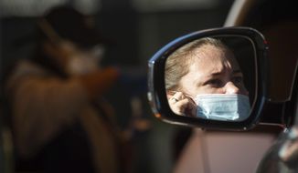 People are tested for COVID-19 at 911 COVID Testing drive-thru on Wednesday, Jan. 5, 2022, near the Getty Center in Los Angeles, where a teenage boy tested positive for the flu and COVID-19. (Sarah Reingewirtz/The Orange County Register via AP)