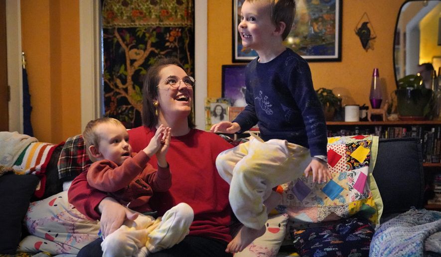 Heather Cimellaro holds her three-year-old son Charlie while his twin brother, Milo, jumps on a couch at their home, Wednesday, Jan. 5, 2022, in Auburn, Maine. Heather Cimellaro is one many parents concerned about the omicron surge and the dilemma it&#39;s posing for families of children too young to be vaccinated. (AP Photo/Robert F. Bukaty)