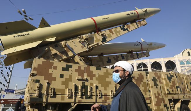 A cleric walks past Zolfaghar, top, and Dezful missiles displayed in a missile capabilities exhibition by the paramilitary Revolutionary Guard a day prior to the second anniversary of Iran&#x27;s missile strike on U.S. bases in Iraq in retaliation for the U.S. drone strike that killed top Iranian general Qassem Soleimani in Baghdad, at Imam Khomeini grand mosque, in Tehran, Iran, Friday, Jan. 7, 2022. Iran put three ballistic missiles on display on Friday, as talks in Vienna aimed at reviving Tehran&#x27;s nuclear deal with world powers flounder. (AP Photo/Vahid Salemi)