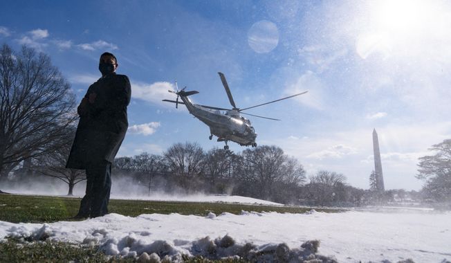 A U.S. Secret Service Special Agent stands as Marine One, with President Joe Biden aboard, lifts off from the South Lawn of the White House blowing snow with the rotor wash, Friday, Jan. 7, 2022, in Washington. Biden is en route to Colorado and Las Vegas. (AP Photo/Alex Brandon)