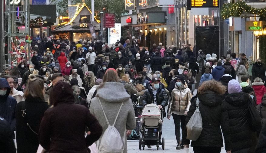 People wear mandatory face masks while walking along a street in Dortmund, Germany, on Dec. 1, 2021. Inflation in the 19 countries that use the euro currency hit a new high of 5.0% in December, breaking the record set the previous month. (AP Photo/Martin Meissner, File)