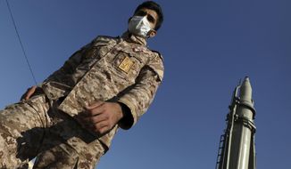 A Revolutionary Guard member walks past Qiam missile displayed in a missile capabilities exhibition by the Guard a day prior to second anniversary of Iran&#39;s missile strike on U.S. bases in Iraq in retaliation for the U.S. drone strike that killed top Iranian general Qassem Soleimani in Baghdad, at Imam Khomeini grand mosque, in Tehran, Iran, Friday, Jan. 7, 2022. Iran put three ballistic missiles on display on Friday, as talks in Vienna aimed at reviving Tehran&#39;s nuclear deal with world powers flounder. (AP Photo/Vahid Salemi)