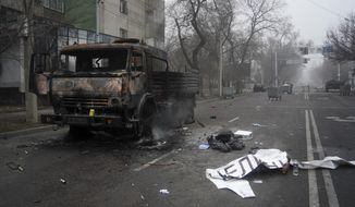 A body of victim covered by a banner, right, lays near to a military truck, which was burned after clashes, in Almaty, Kazakhstan, Thursday, Jan. 6, 2022. Kazakhstan&#39;s president authorized security forces on Friday to shoot to kill those participating in unrest, opening the door for a dramatic escalation in a crackdown on anti-government protests that have turned violent. The Central Asian nation this week experienced its worst street protests since gaining independence from the Soviet Union three decades ago, and dozens have been killed in the tumult. (AP Photo/Vladimir Tretyakov/NUR.KZ via AP)