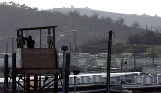 In this Sept. 10, 2002, file photo a U.S. Army military police officer looks through binoculars from a guard tower at Camp Delta where 598 detainees from some 43 countries are being held at the U.S. Naval Base at Guantanamo Bay, Cuba. The 20th anniversary of the first prisoners&#39; arrival at the Guantanamo Bay detention center is on Tuesday, Jan. 11, 2022. There are now 39 prisoners left. At its peak, in 2003, the detention center held nearly 680 prisoners. (AP Photo/Lynne Sladky, File)