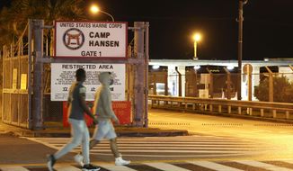 People walk past the U.S. Marine Corps&#39; Camp Hansen, in Kin, Okinawa prefecture, southern Japan, on Jan. 6, 2022. Okinawa, a southwestern group of islands, which houses most of the 55,000 U.S. troops in Japan, is among the three prefectures where new restrictions to curb the spread of the coronavirus infections kicked in Sunday, Jan. 9.(Kyodo News via AP)