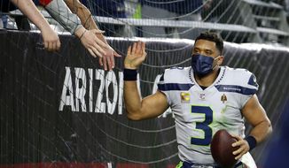 Seattle Seahawks quarterback Russell Wilson gets high-fives from fans after the Seahawks defeated the Arizona Cardinals after an NFL football game Sunday, Jan. 9, 2022, in Glendale, Ariz. The Seahawks won 38-30. (AP Photo/Ralph Freso)
